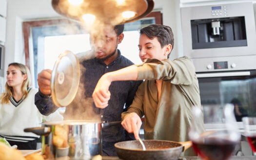 friends cook pasta with sauce together in shared kitchen
